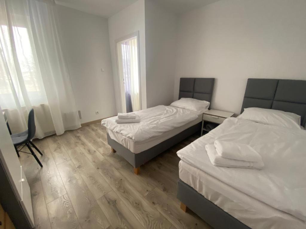 two beds in a small room with white walls at Apartamenty Zatorze in Leszno