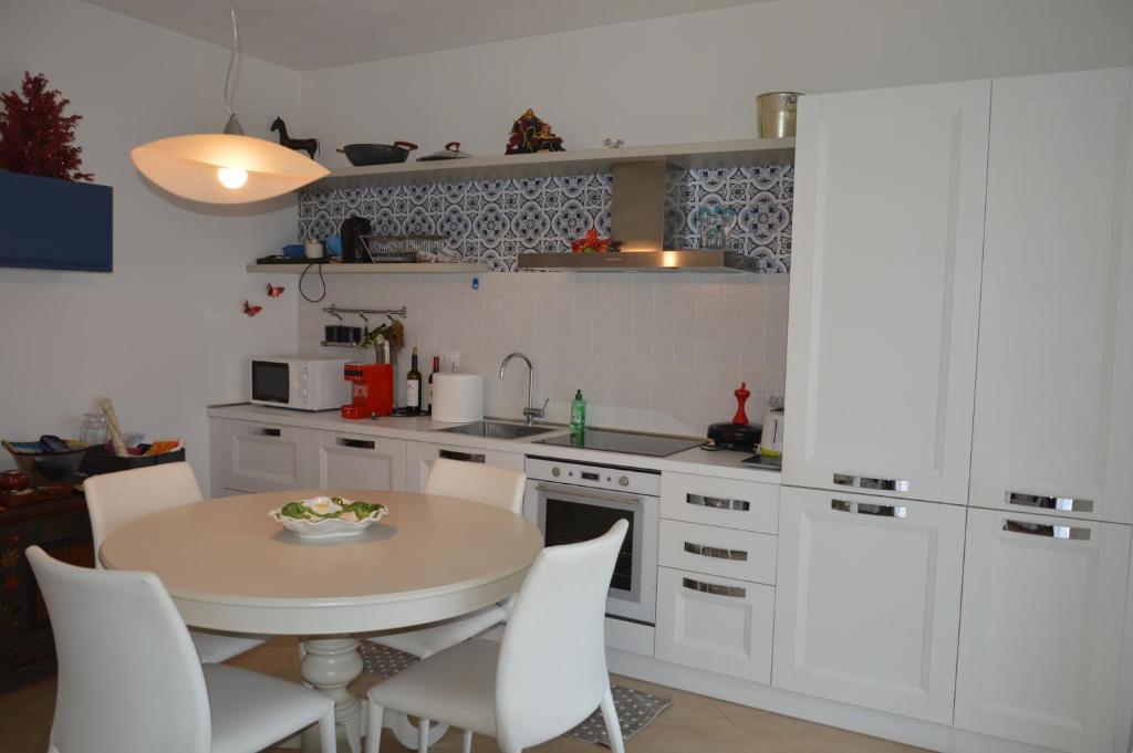 a kitchen with a table and white cabinets at Salice ottimo trilocale con terrazza pranzabile in Marina di Castagneto Carducci