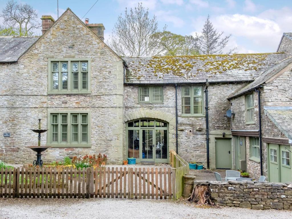 an old stone house with a wooden fence at The Rockery in Shap