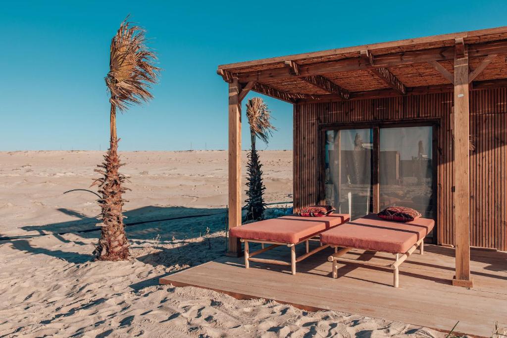 a house in the desert with two chairs and a palm tree at Selina Dakhla in Dakhla