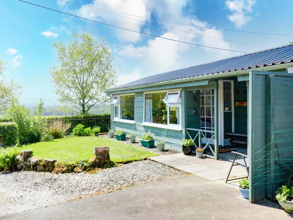 a green house with a garden in front of it at The Old School Bike Shed in Stirling