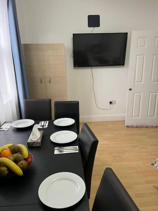 a black table with white plates on it with a bowl of fruit at 001- Lovely 3-bedroom very close to Oxford Street in London