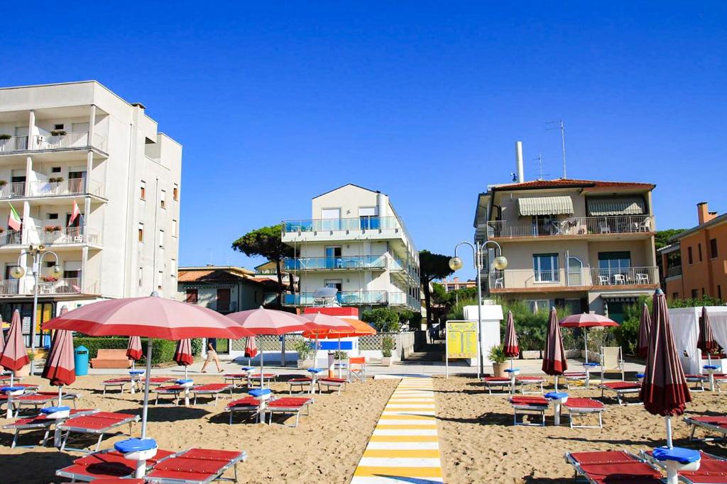 einen Strand mit Stühlen, Sonnenschirmen und Gebäuden in der Unterkunft Jesolo Sun Beach House - Host Solution in Lido di Jesolo