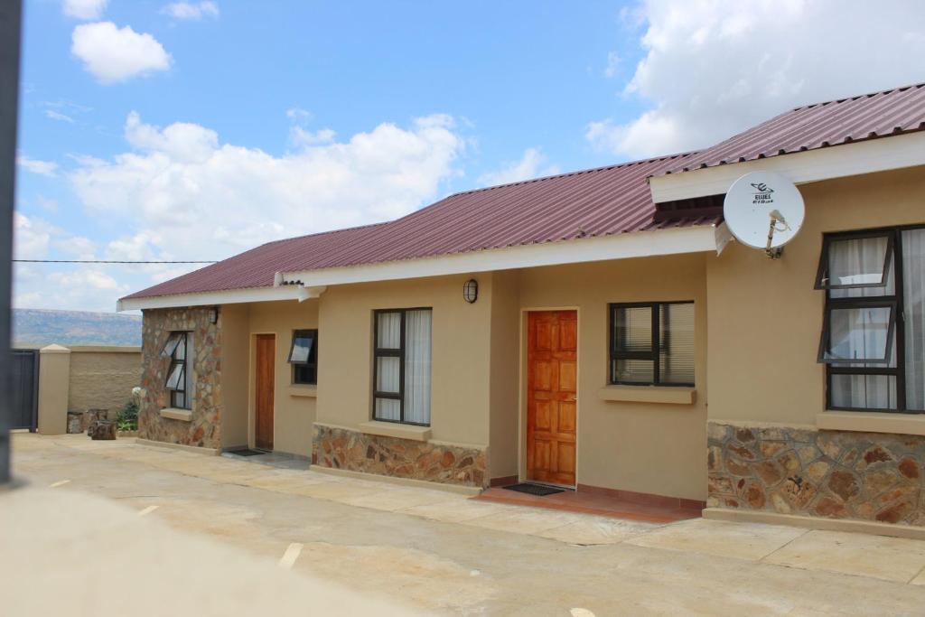 una pequeña casa con techo rojo en ONESI Guest House, en Maseru