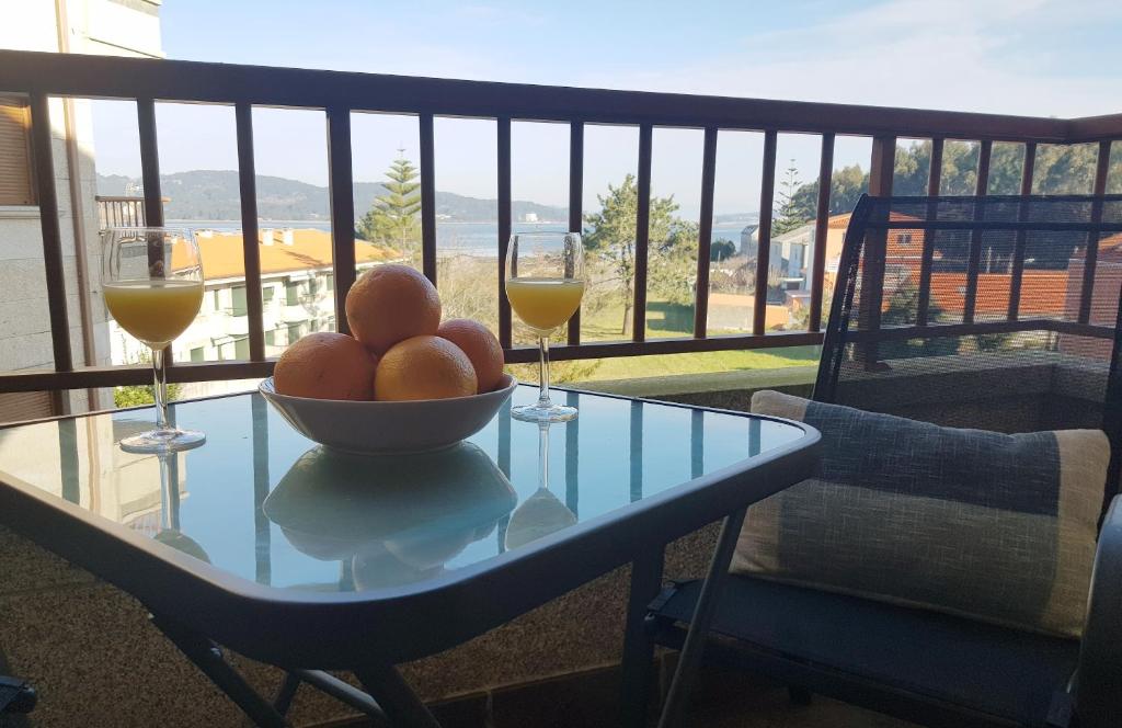 - une table avec un bol de fruits et deux verres de vin dans l'établissement MARISMA DE A LANZADA, à Sanxenxo