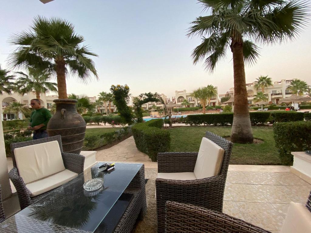 a patio with a table and chairs and palm trees at Renoviertes Luxusapartment Sunny Lakes 1 Sharm El-Sheikh nun auch für Langzeitmieter buchbar in Sharm El Sheikh