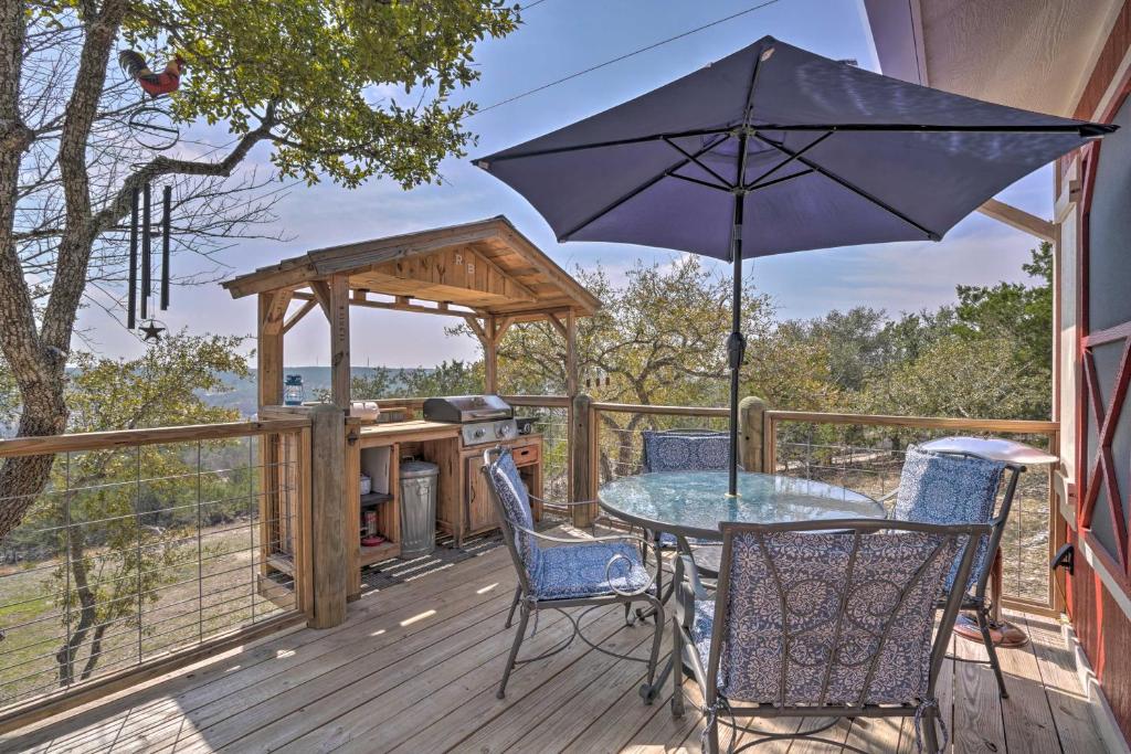un tavolo e sedie su una terrazza con ombrellone di Kerrville Converted Barn Tiny Home with Kayaks! a Kerrville