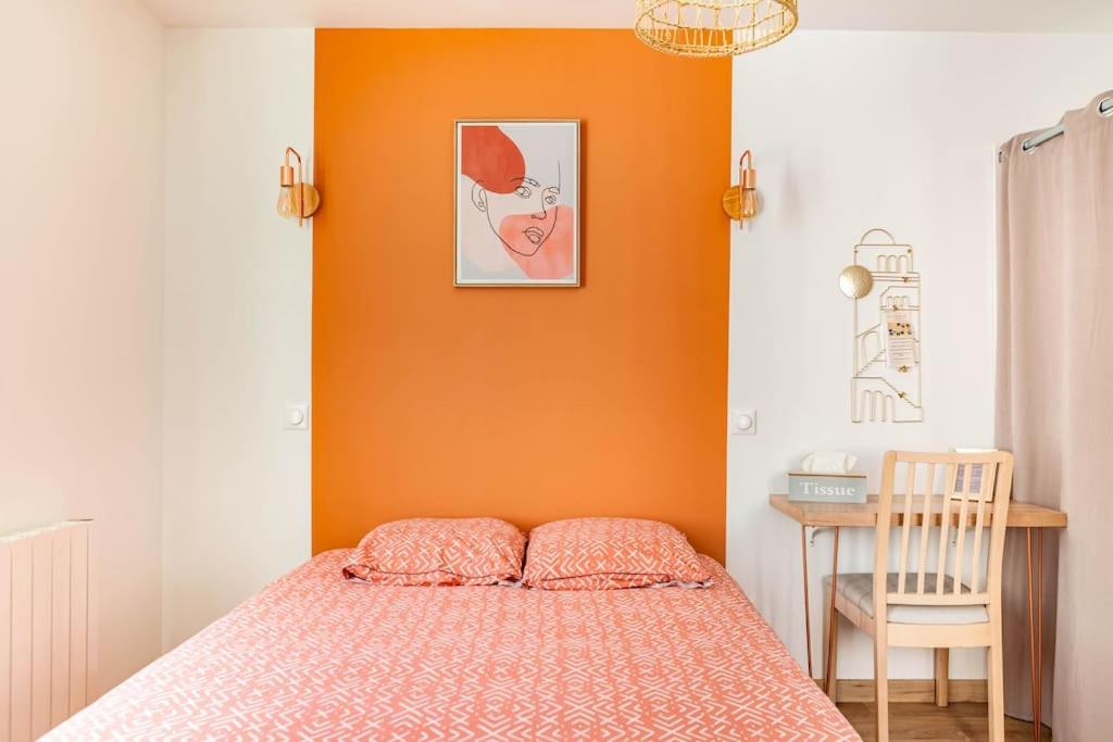 sypialnia z pomarańczową ścianą z łóżkiem i krzesłem w obiekcie Maison tourangelle chic & cosy avec cour w Tours