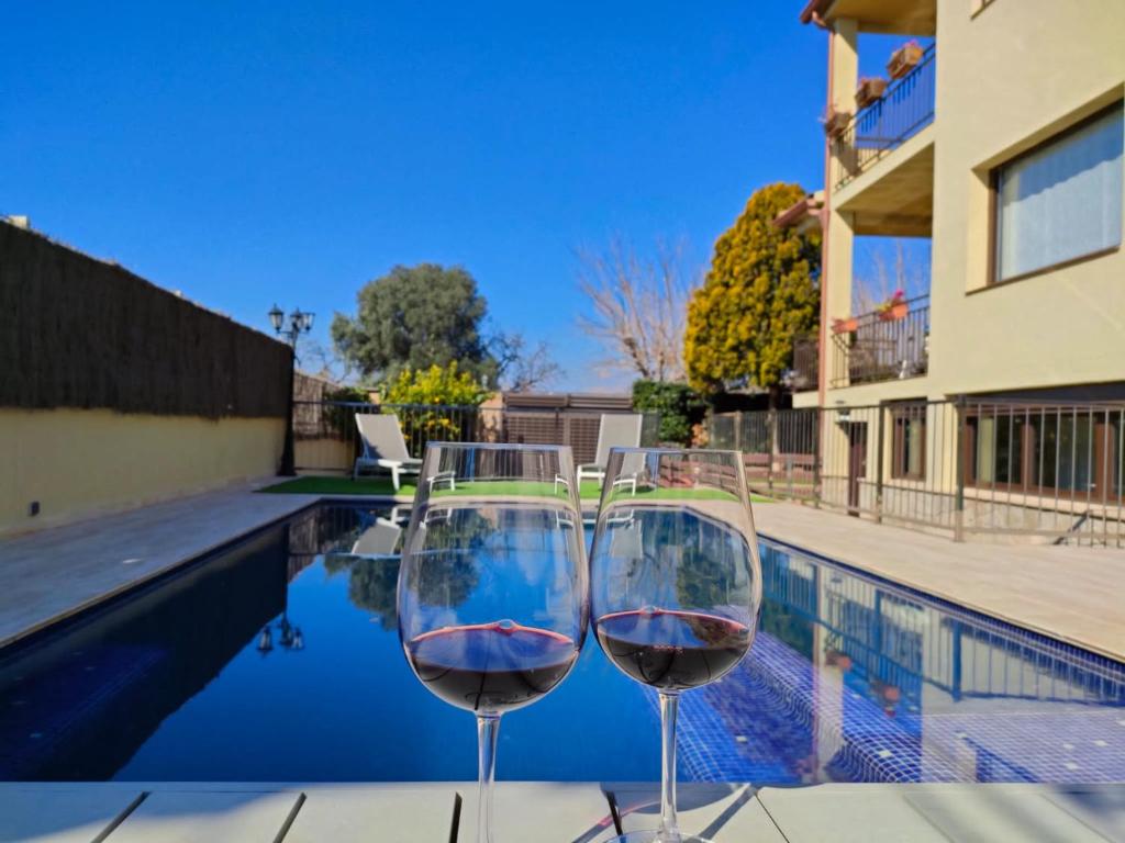 dos copas de vino sentadas junto a una piscina en Casa, parque natural de Montserrat cerca Barcelona en Collbató