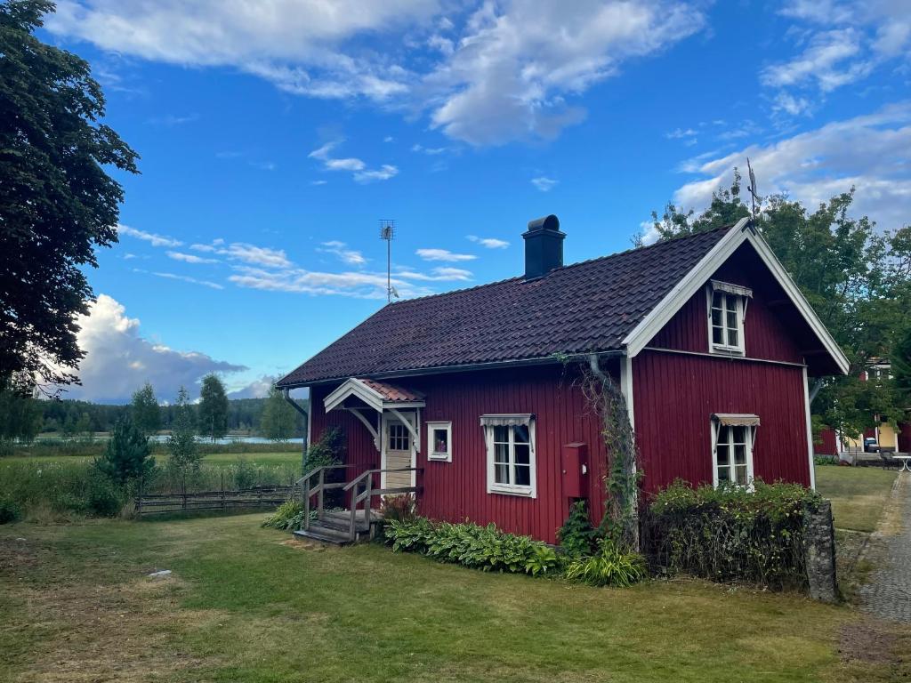 a red house in a field with a blue sky at Runeholm in Vimmerby