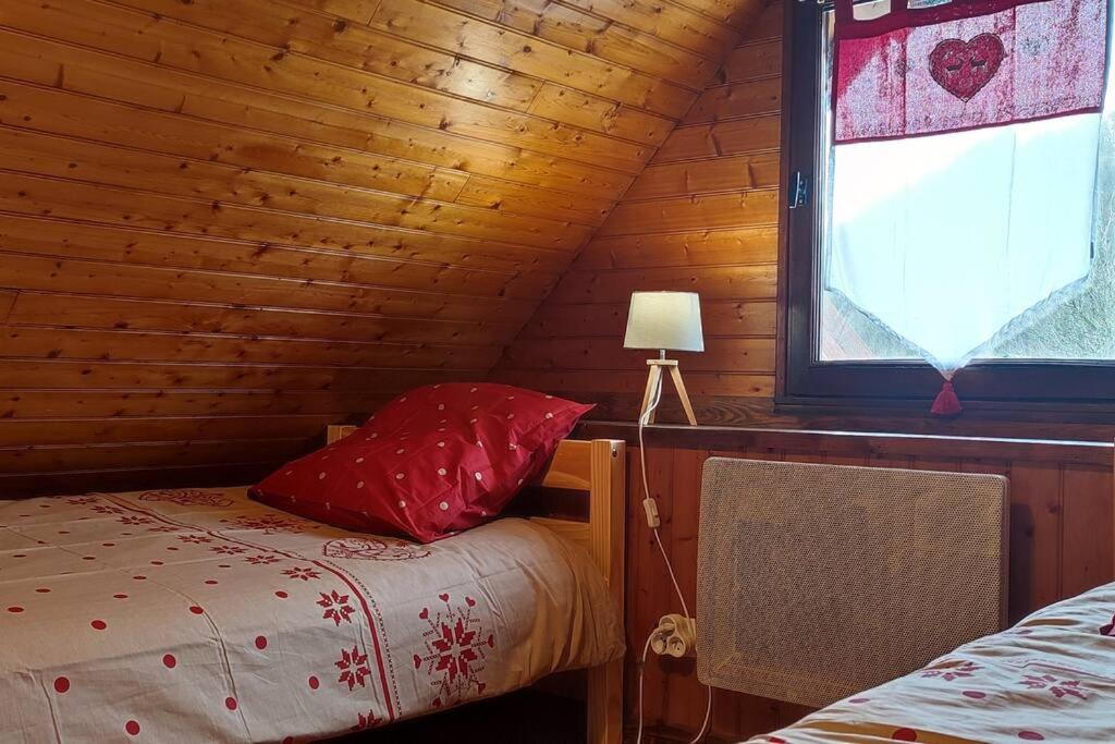 ein Schlafzimmer mit einem Bett und einem Fenster in einem Blockhaus in der Unterkunft LA RUSTIQUE DU BOUT DU LAC in Chambon-sur-Lac
