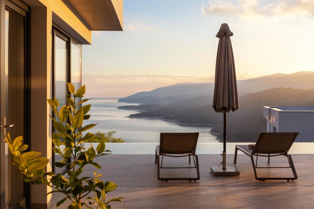 a balcony with two chairs and an umbrella at Green Tree Villas in Rabac