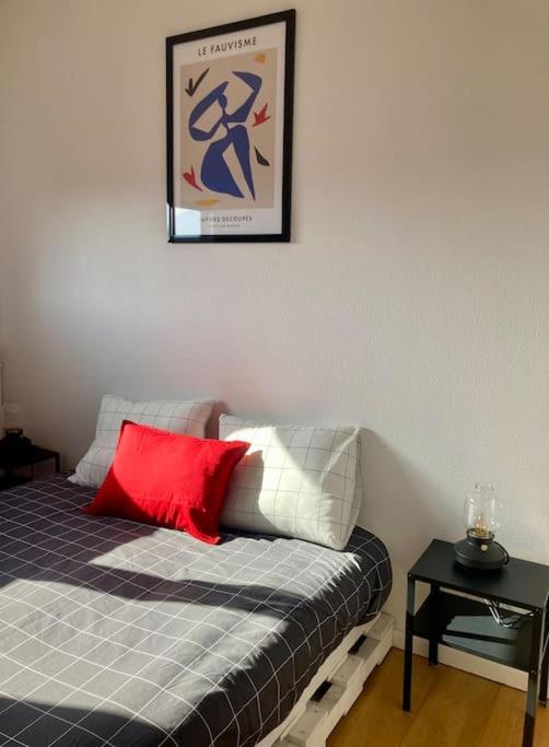 a bedroom with a bed with a red pillow and a table at Charmant Appartement Pop - Arty in Thonon-les-Bains