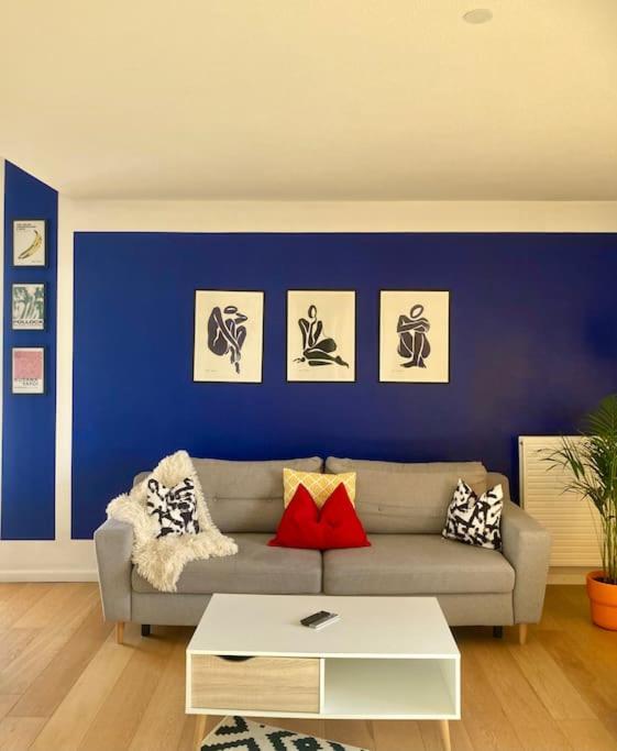 a living room with a couch and a blue wall at Charmant Appartement Pop - Arty in Thonon-les-Bains