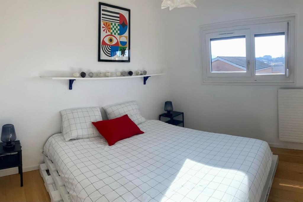 a bedroom with a white bed with a red pillow at Charmant Appartement Pop - Arty in Thonon-les-Bains