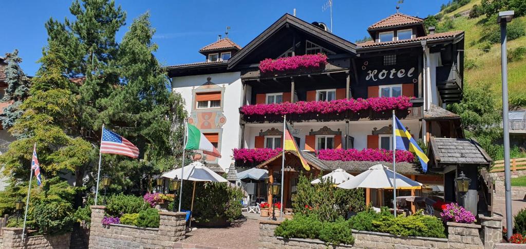 a hotel with flags and umbrellas in front of it at Villa Martha Vintage Hotel-B&B in Santa Cristina Gherdëina