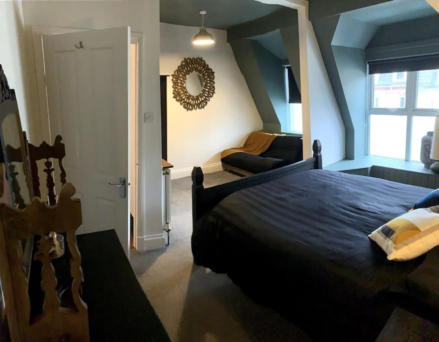 a bedroom with a large bed and a living room at Chic Townhouse near Tunnels Beaches Ilfracombe in Ilfracombe