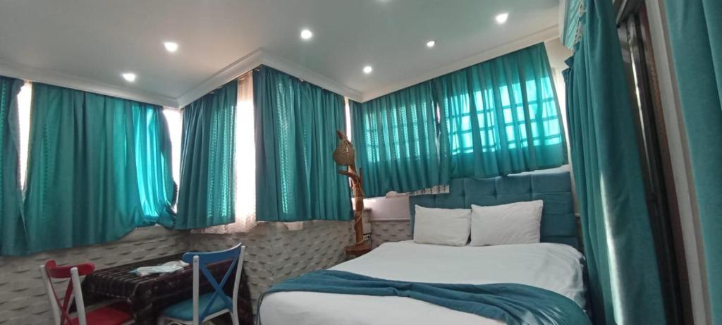 a bedroom with green curtains and a bed and a table at ŞİRİNYER APART OTEL in Izmir