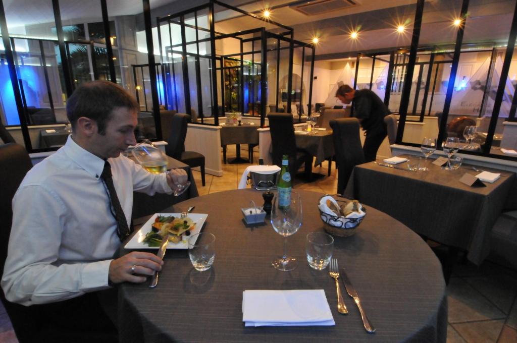 a man sitting at a table with a plate of food at Hôtel Restaurant & Spa Plaisir in Le Bois-Plage-en-Ré