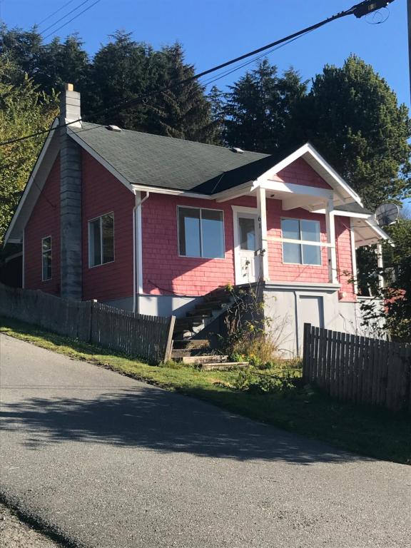 a red house with a fence in front of it at Alert Bay Sweet Home in Alert Bay