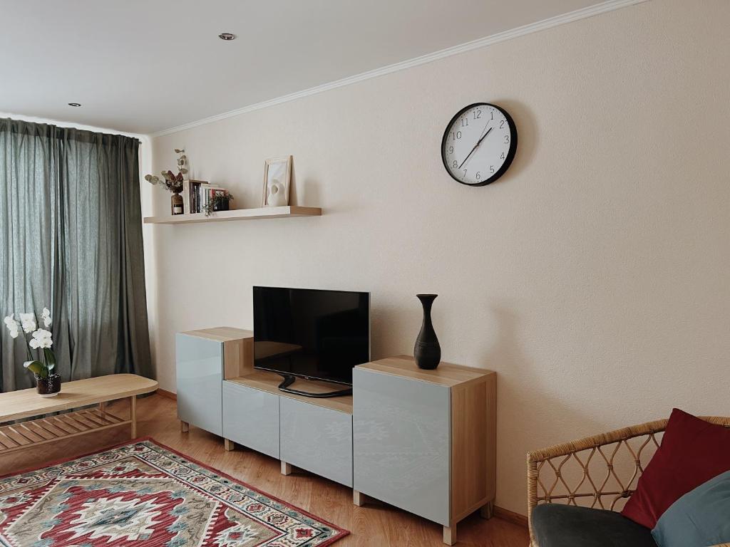 sala de estar con TV y reloj en la pared en Rauna Apartment NR 8, en Rauna