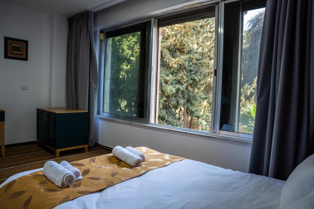 a bedroom with two towels on a bed with windows at Jerusalem Boutique Hotel in Jerusalem