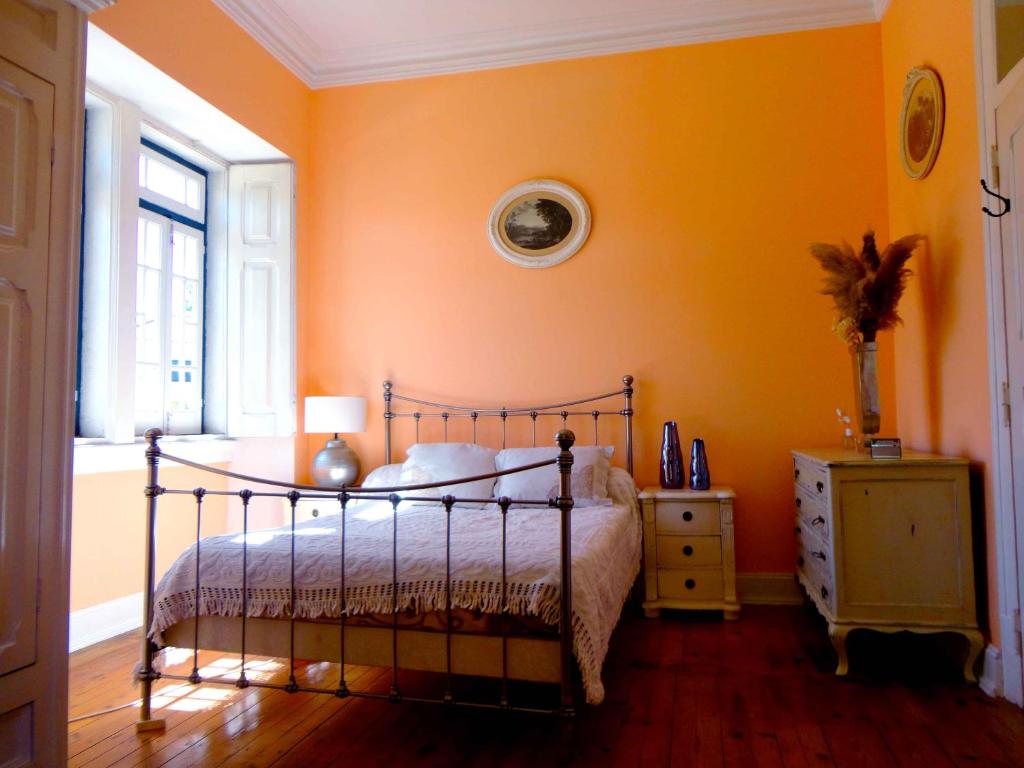 sypialnia z pomarańczowymi ścianami, łóżkiem i oknem w obiekcie B&B Quarto Rosa Estilo Romântico 