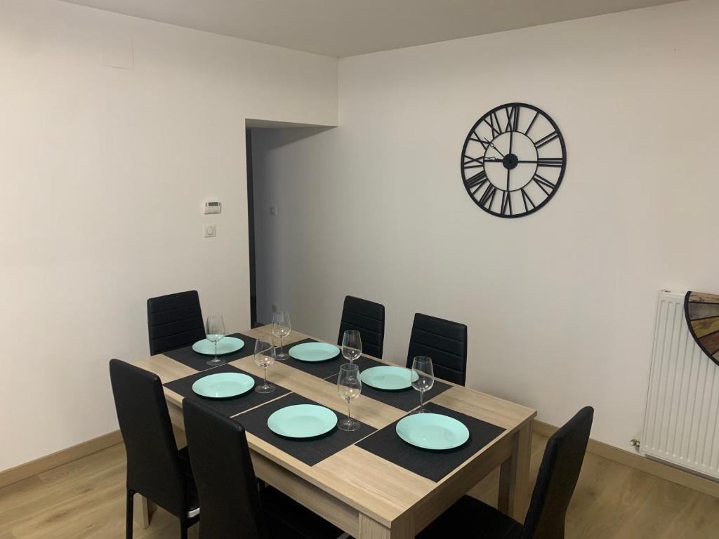 a dining room table with chairs and a clock on the wall at Appartement moderne in Saint-Mihiel