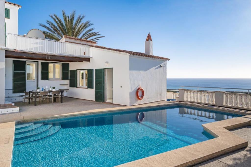 a house with a swimming pool next to the ocean at Villa Atalis in Son Bou
