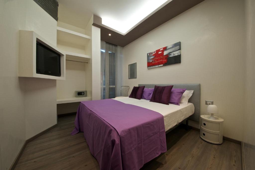 a bedroom with a bed with purple sheets and a tv at Roma Naif Rooms in Rome
