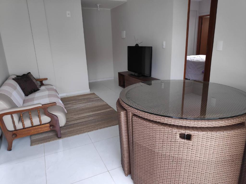 - un salon avec une table en osier et un canapé dans l'établissement Apartamento Ar condicionado, varanda, 2 vagas garagem, à Muriaé