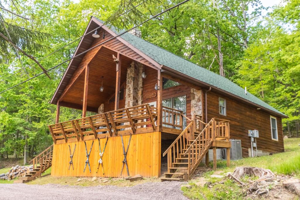 eine Hütte im Wald mit einer großen Terrasse in der Unterkunft Fawn View Cabin in McHenry