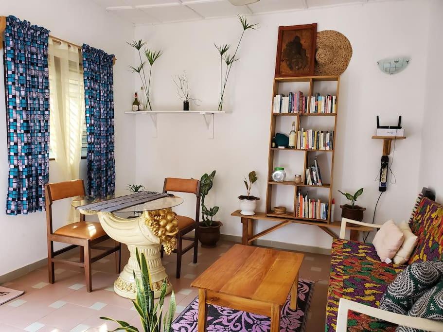 a living room with a table and chairs and a book shelf at Maison fleurie Ouidah in Ouidah