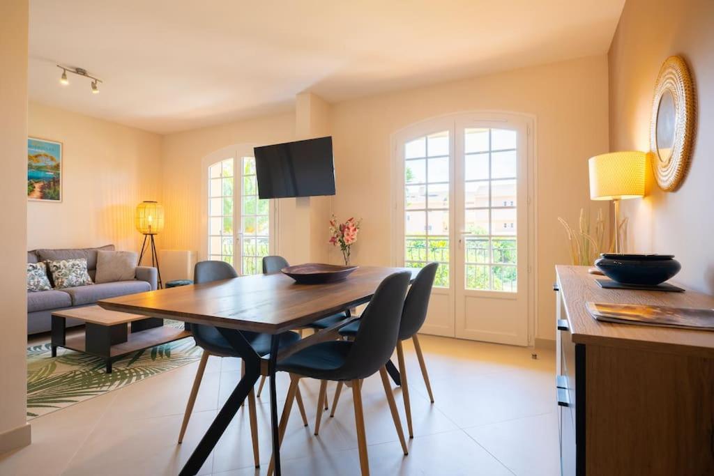 a kitchen and living room with a wooden table and chairs at Les Jardins de Provence • Beau Rivage • Proche mer in Carqueiranne