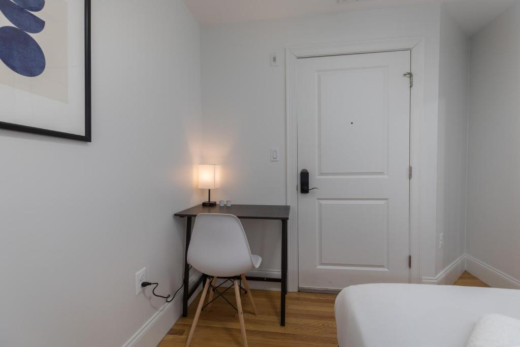 a bedroom with a desk and a white door and a chair at West Broadway Quarters by Thatch in Boston