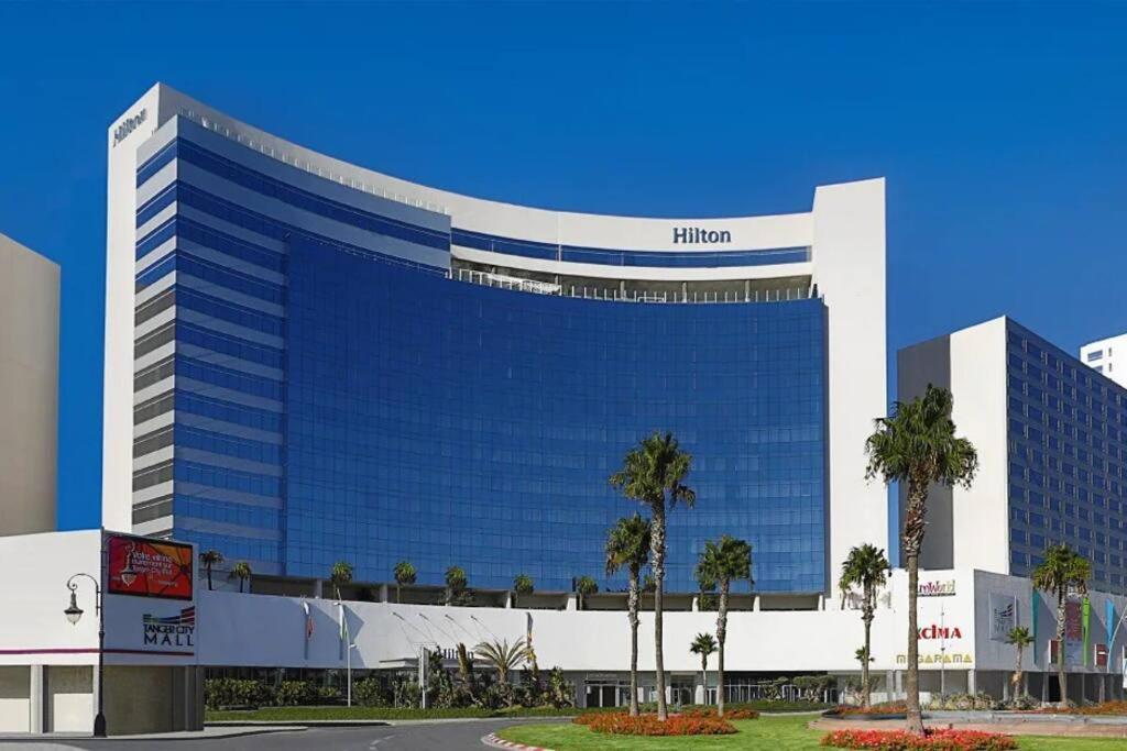 un grand bâtiment bleu avec des palmiers devant lui dans l'établissement Luxury Apartment Hilton 5*, à Tanger