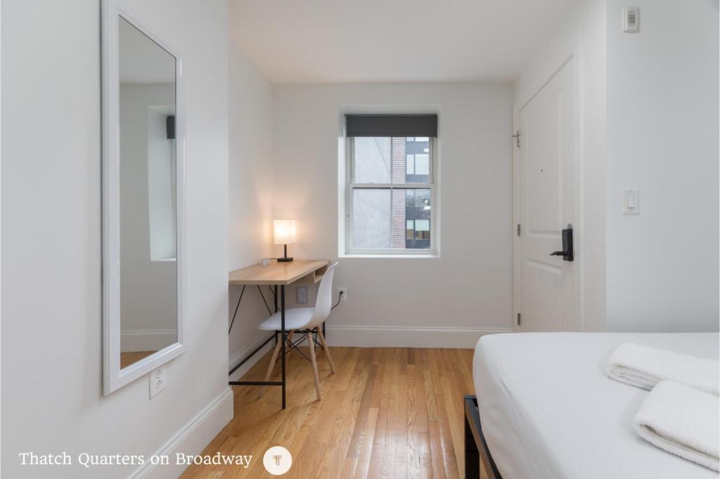 a bedroom with a bed and a desk and a window at West Broadway Quarters by Thatch in Boston