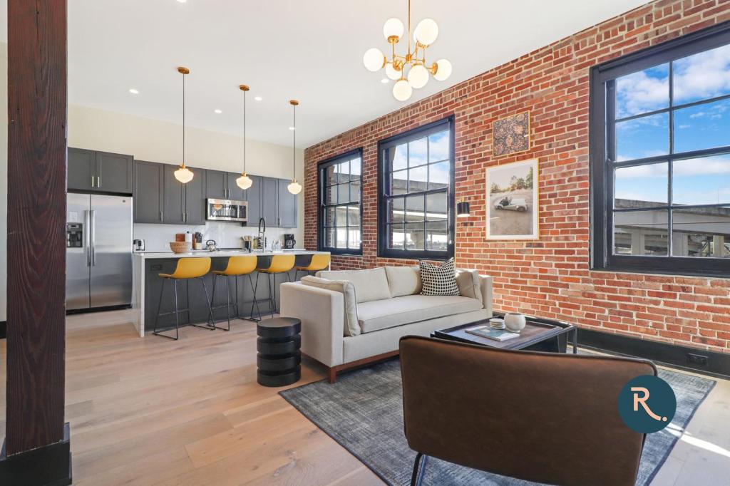 an open living room and kitchen with a brick wall at Roami at The Lola in New Orleans