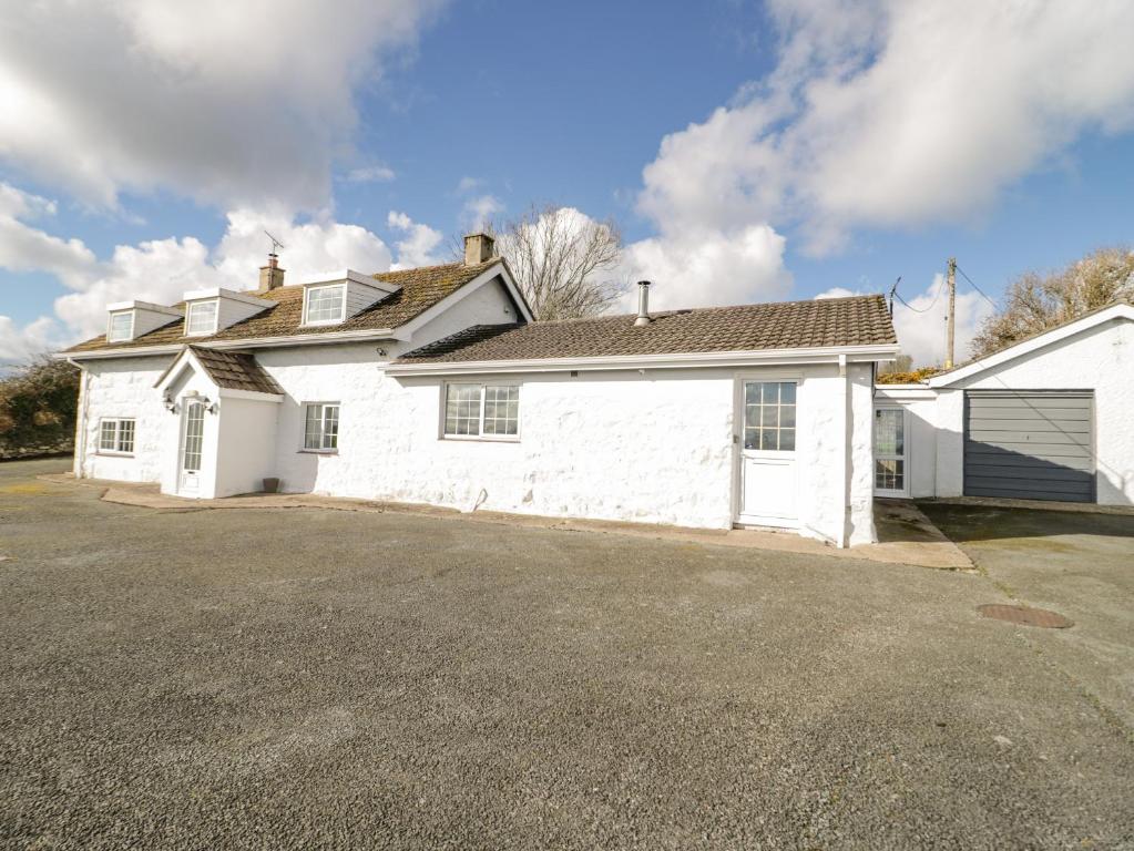 une maison blanche avec un garage dans une allée dans l'établissement Rhous, à Llanallgo