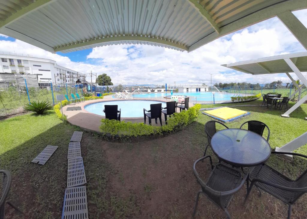 a patio with a table and chairs and a pool at Parque del Café Apartamentos con Piscina in La Tebaida