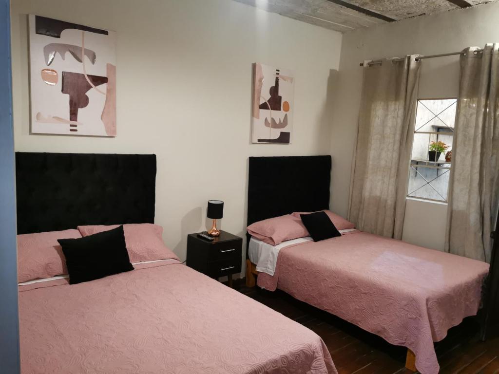 a room with two beds with pink sheets and a window at Hermoso departamento en el centro ciudad, casa M MELGAR in Arequipa