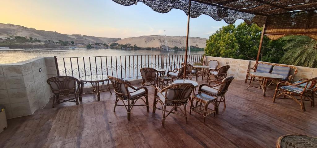a deck with tables and chairs and a view of a river at Meshra Katto in Aswan