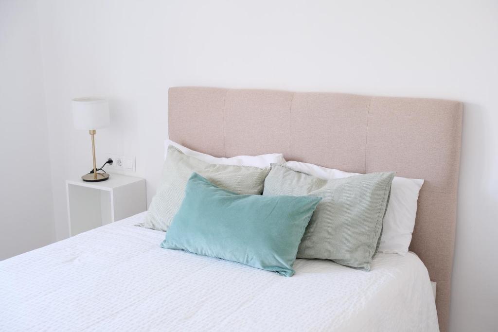 Una cama blanca con cuatro almohadas. en AOVE Suite, en Jaén