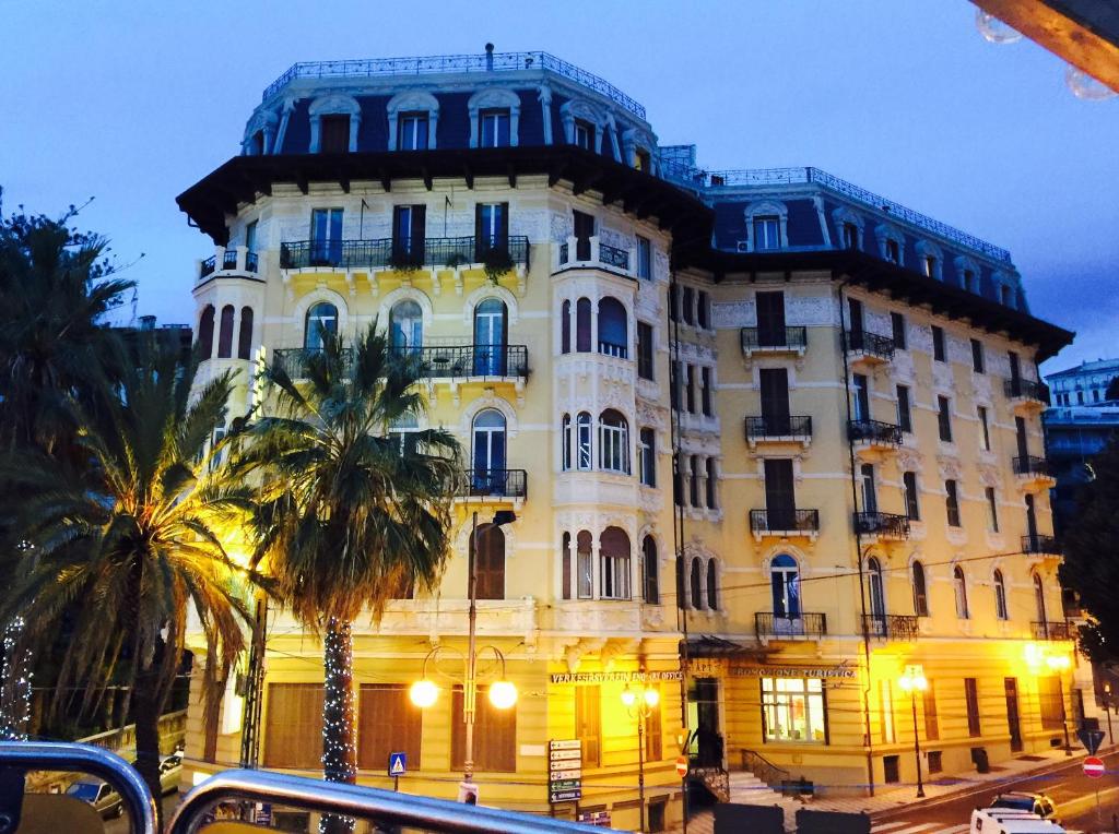 a large building with palm trees in front of it at Lolli Palace Hotel in Sanremo