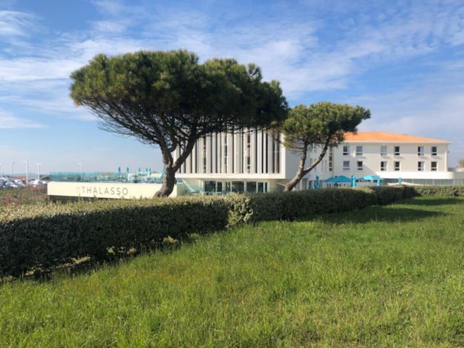 un bâtiment avec un arbre devant un champ dans l'établissement Studio-terrasse 3* bord de mer Châtelaillon plage, à Châtelaillon-Plage