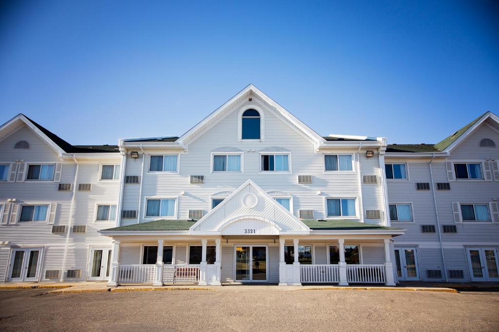 a large white apartment building with a front porch at Travelodge Suites by Wyndham Regina - Eastgate Bay in Regina