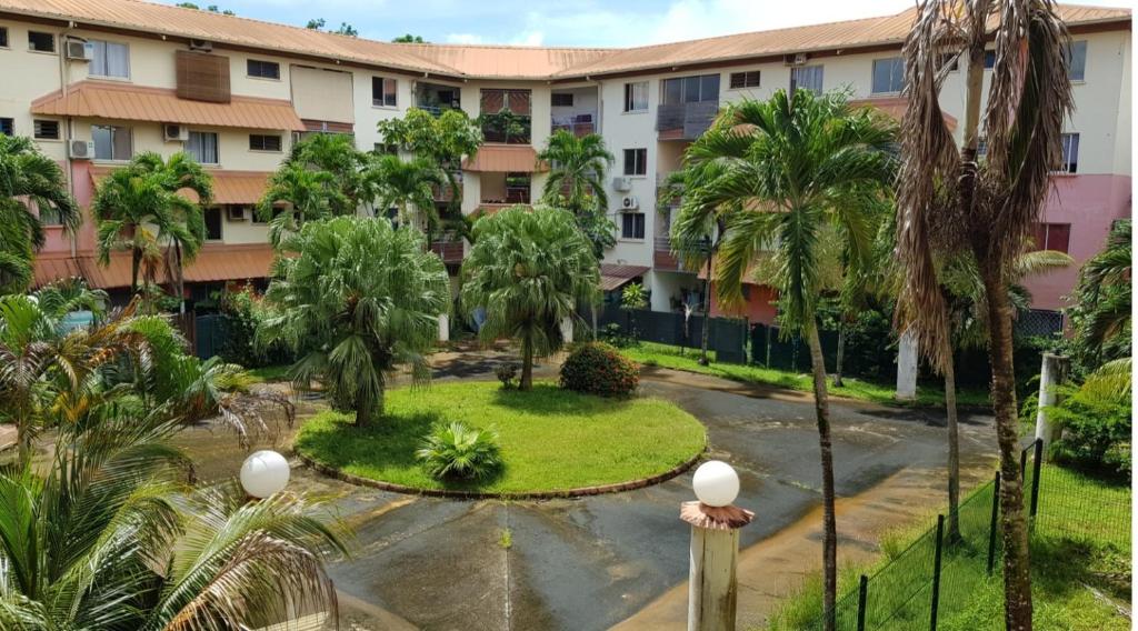 an apartment complex with palm trees and a courtyard at Le Studio de Jo in Cayenne