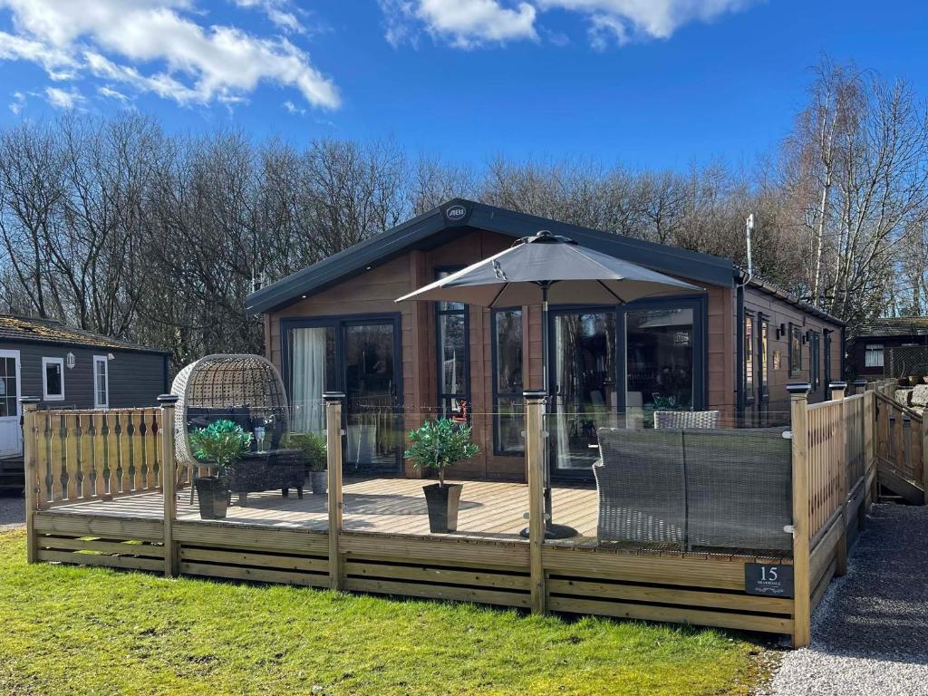 a small house with a deck with an umbrella at Lindale Lodge in Carnforth