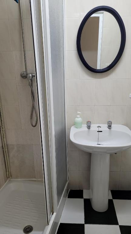a bathroom with a sink and a shower with a mirror at Pensión San Benito Abad in Seville