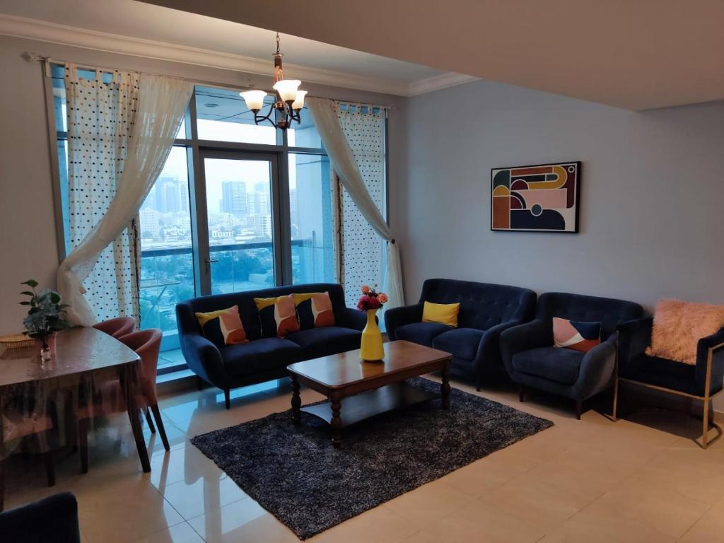 a living room with blue couches and a table at Walk to the Beach, Charming 3-Bedroom Home in Ajman Corniche Residences in Ajman 